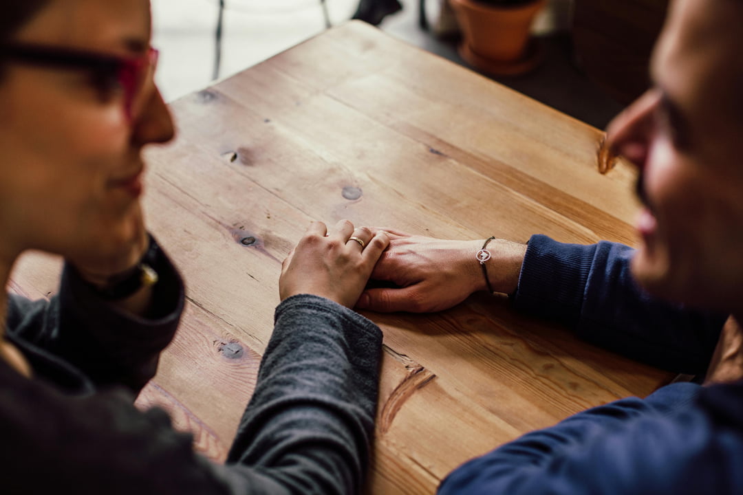 a couple holding hands at a coffee shop