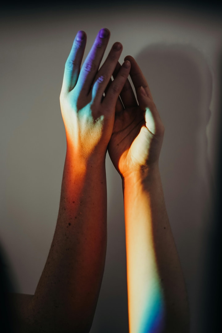 holding hands with a rainbow reflection