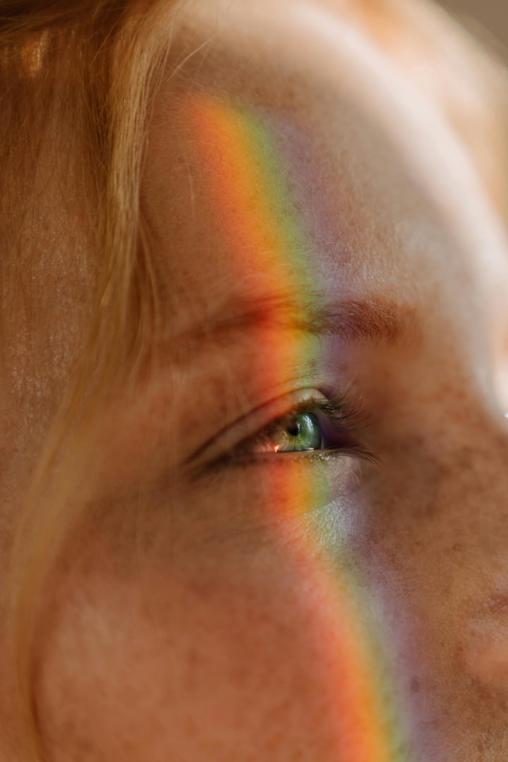 a girl with a rainbow reflecting on her eye