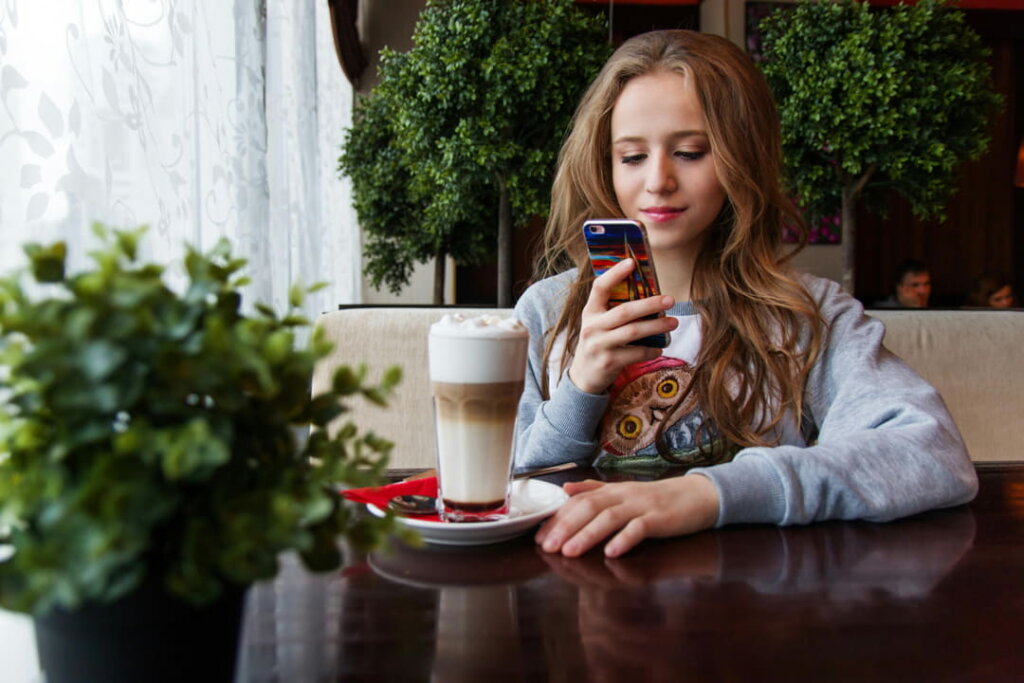 a teenage girl on her phone in a coffee shop